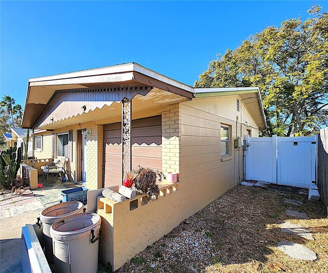 7521 Coventry Dr, Port Richey, FL 34668 - view of home's exterior featuring brick siding, a gate, and a patio area