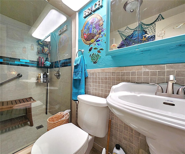 bathroom with tiled shower, sink, tile walls, and toilet