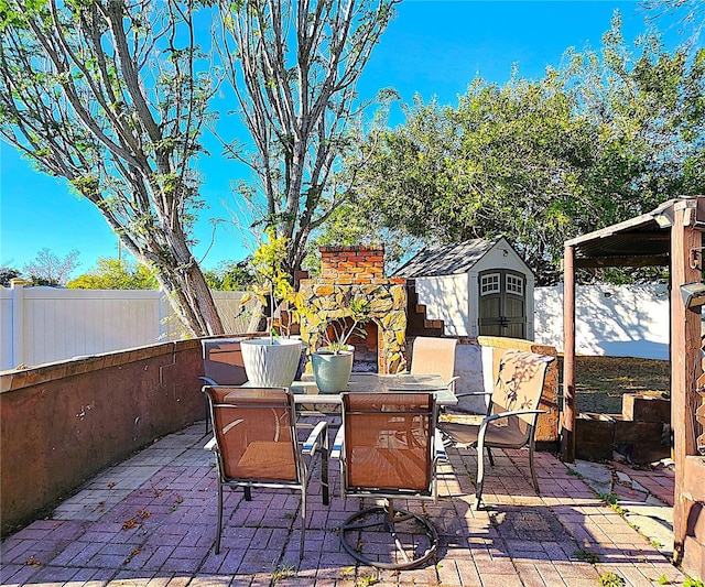 view of patio featuring an outdoor stone fireplace and a storage unit