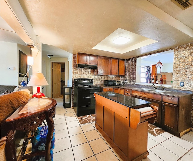 kitchen featuring light tile patterned flooring, a center island, a tray ceiling, and black appliances