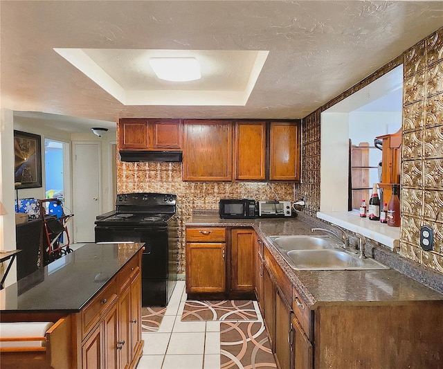 kitchen featuring black appliances, a raised ceiling, sink, light tile patterned flooring, and kitchen peninsula