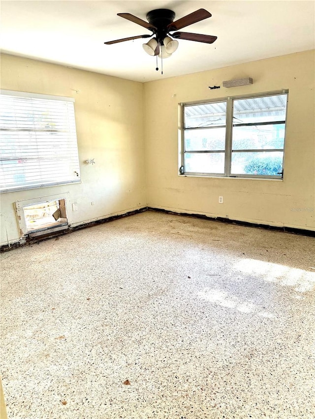 empty room with ceiling fan and plenty of natural light