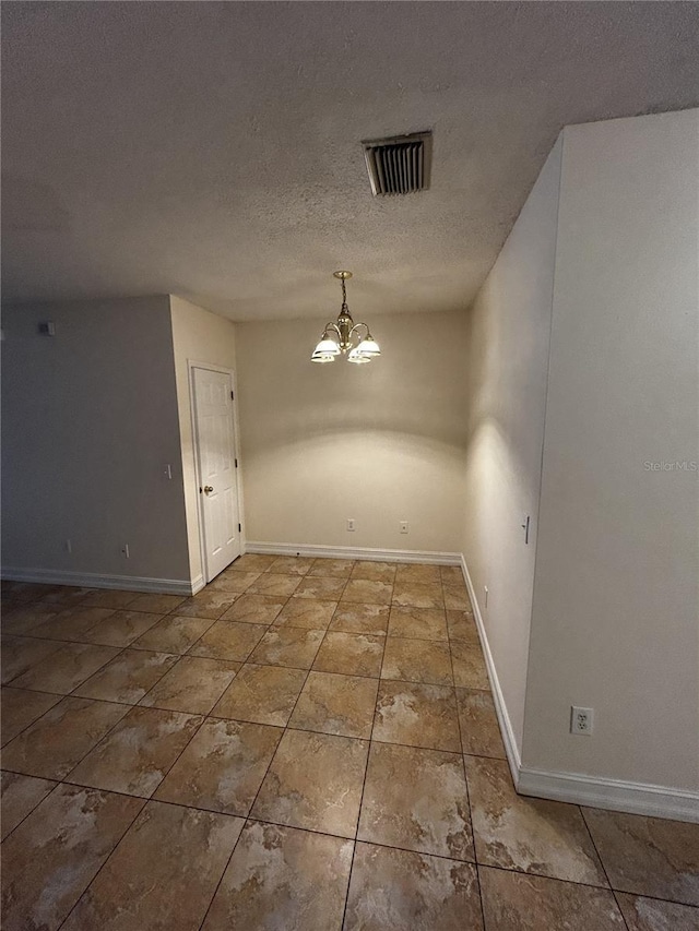 unfurnished dining area with a chandelier and a textured ceiling