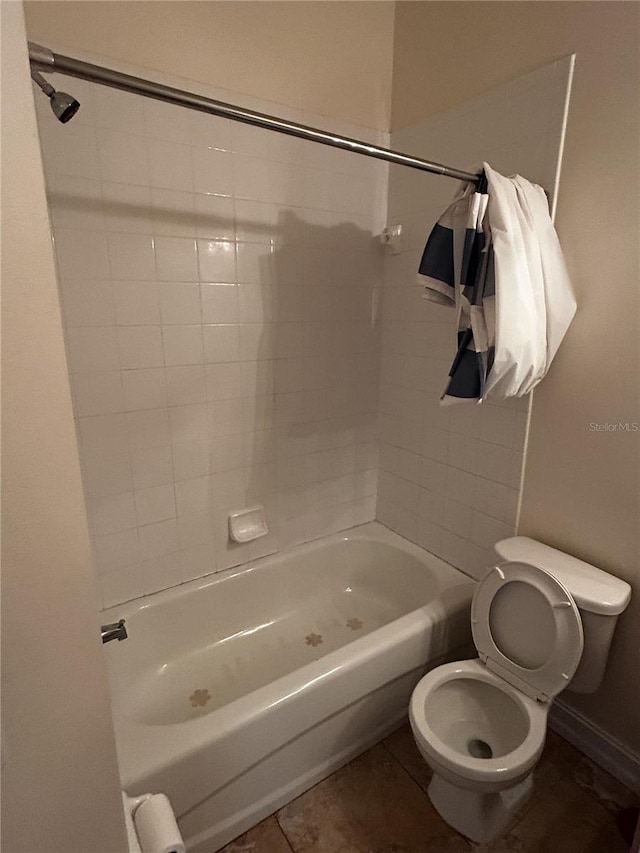 bathroom featuring tile patterned flooring, tiled shower / bath combo, and toilet