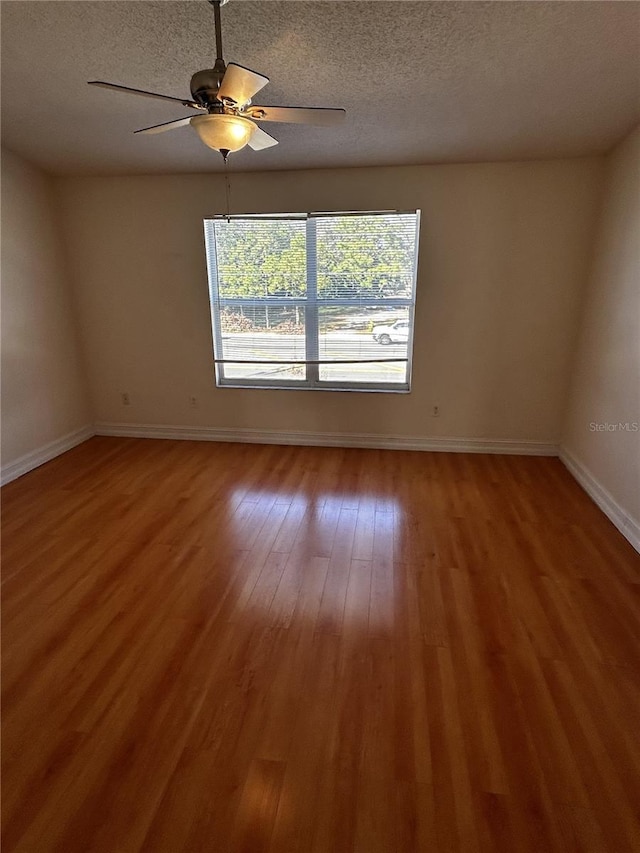 empty room with hardwood / wood-style flooring, ceiling fan, and a textured ceiling