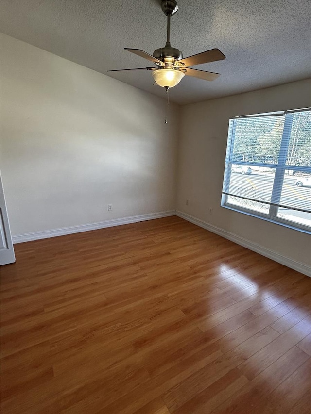 empty room with ceiling fan, hardwood / wood-style floors, and a textured ceiling