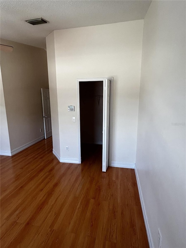 empty room with a textured ceiling and dark hardwood / wood-style flooring