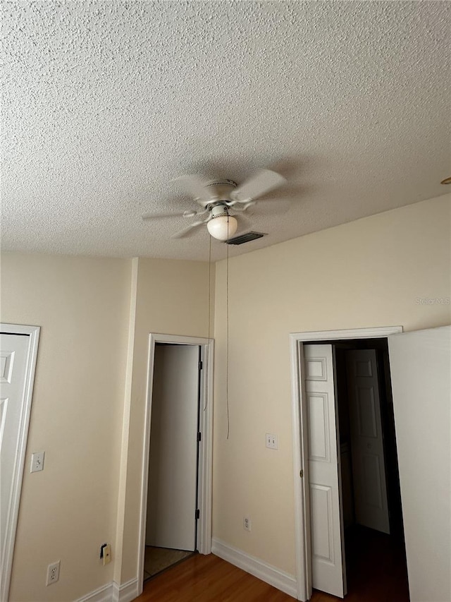 unfurnished bedroom featuring a closet, ceiling fan, hardwood / wood-style floors, and a textured ceiling