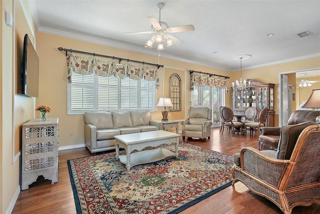 living room with ceiling fan with notable chandelier, dark hardwood / wood-style flooring, ornamental molding, and a textured ceiling