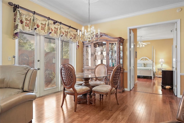 dining area featuring crown molding, wood-type flooring, and ceiling fan with notable chandelier