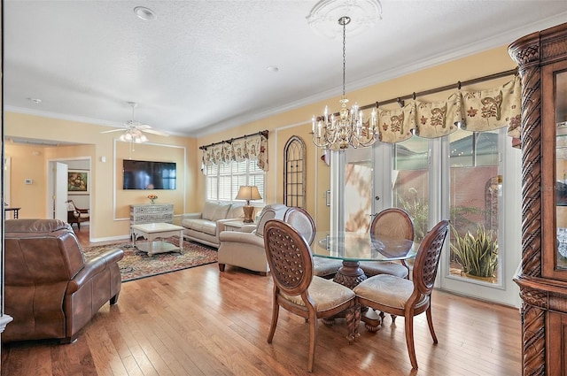 dining space with french doors, light hardwood / wood-style flooring, crown molding, a textured ceiling, and ceiling fan with notable chandelier