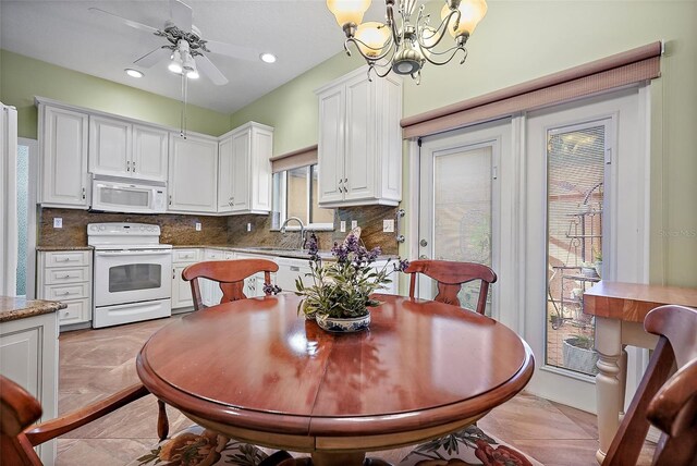 tiled dining room featuring sink and ceiling fan with notable chandelier