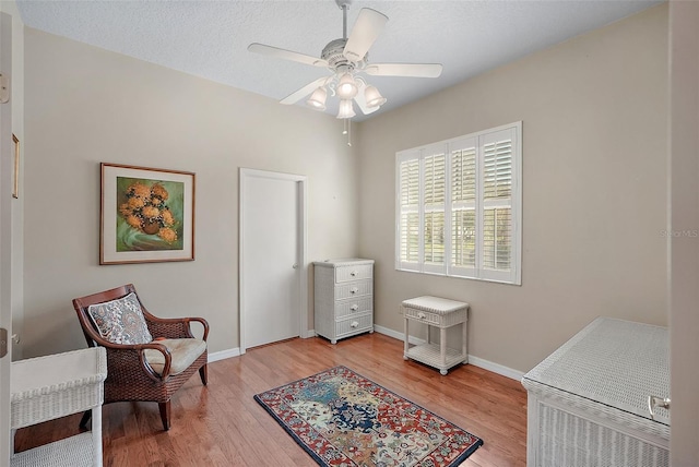 sitting room with a textured ceiling, light hardwood / wood-style flooring, and ceiling fan