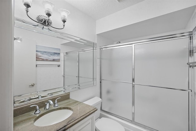 full bathroom featuring toilet, combined bath / shower with glass door, a textured ceiling, and vanity