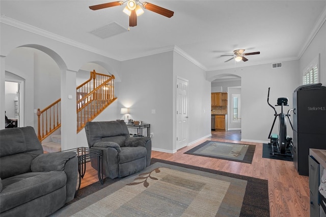 living room with hardwood / wood-style flooring, ceiling fan, and ornamental molding