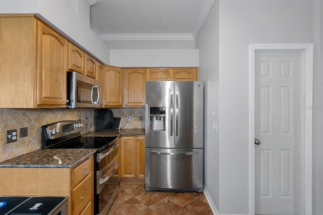 kitchen featuring decorative backsplash, appliances with stainless steel finishes, dark stone counters, dark tile patterned floors, and crown molding