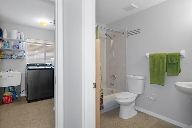 full bathroom featuring tile patterned floors, toilet, tiled shower / bath combo, and washer / dryer