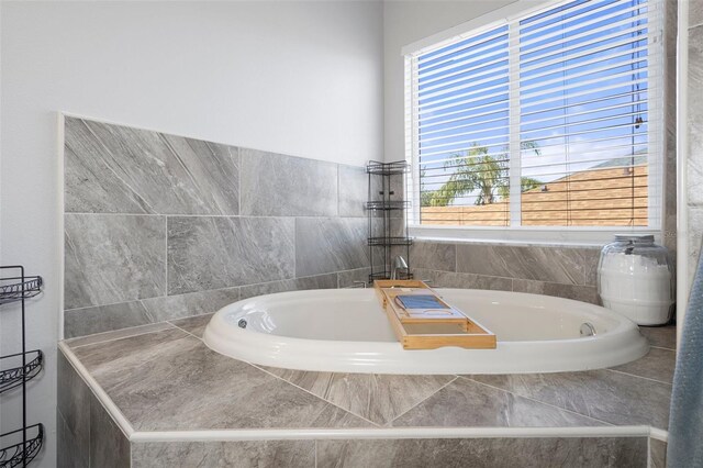 bathroom with a healthy amount of sunlight and tiled tub