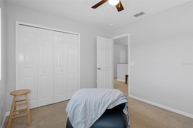 bedroom featuring ceiling fan, light carpet, and a closet