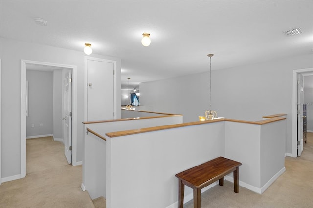 kitchen with kitchen peninsula, pendant lighting, light colored carpet, and a kitchen breakfast bar