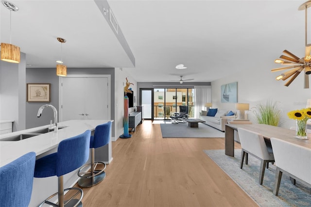 kitchen with pendant lighting, light wood-type flooring, ceiling fan, and sink