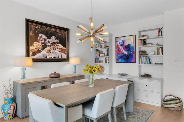 dining room with built in shelves, an inviting chandelier, and light wood-type flooring