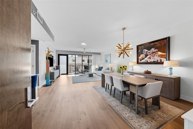 dining area featuring light hardwood / wood-style floors and ceiling fan with notable chandelier