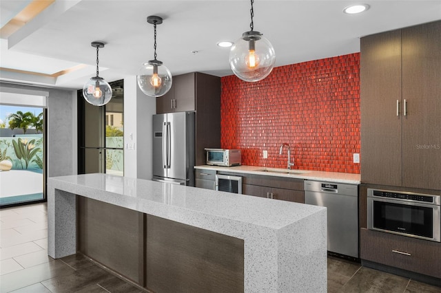 kitchen featuring decorative light fixtures, sink, light stone countertops, and stainless steel appliances