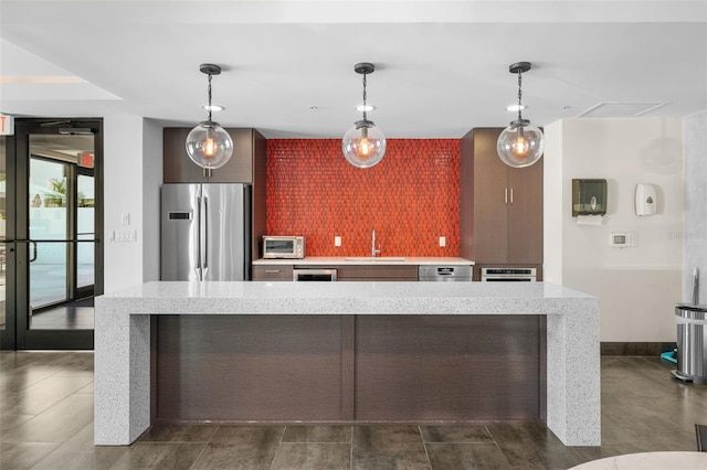 kitchen featuring decorative light fixtures, a kitchen island, sink, and stainless steel refrigerator with ice dispenser