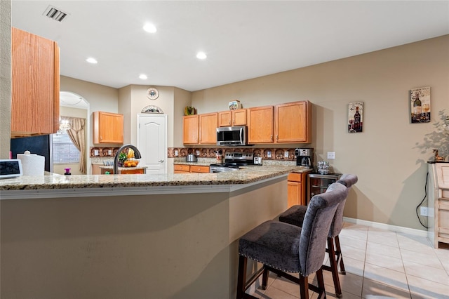 kitchen featuring sink, light stone counters, stainless steel appliances, and tasteful backsplash