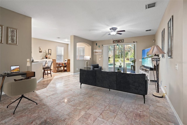 living room with ceiling fan and a textured ceiling