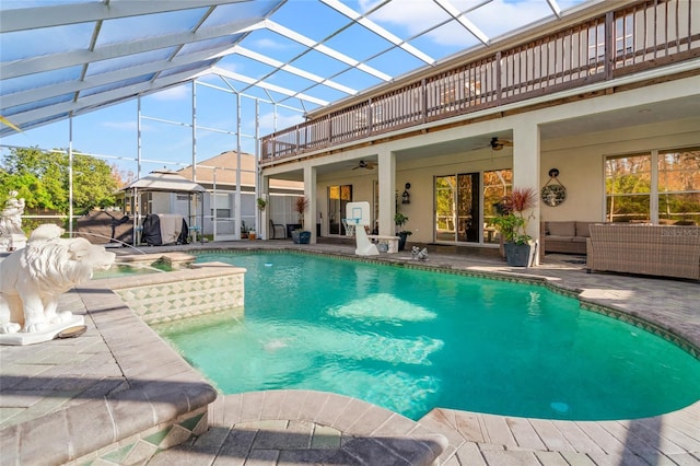 view of swimming pool with ceiling fan, a lanai, an outdoor living space, a hot tub, and a patio area