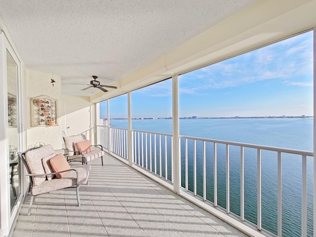 unfurnished sunroom with a water view and ceiling fan