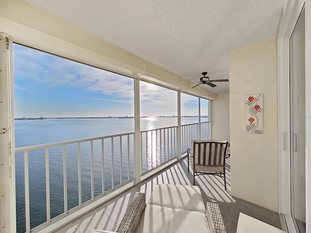 unfurnished sunroom featuring a water view and ceiling fan