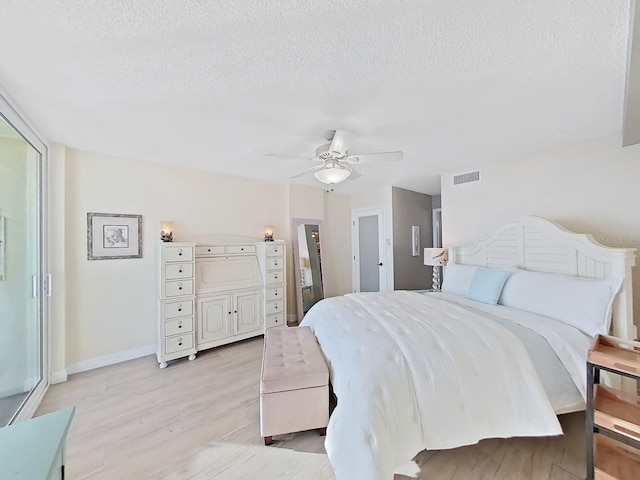 bedroom with ceiling fan, light hardwood / wood-style floors, and a textured ceiling