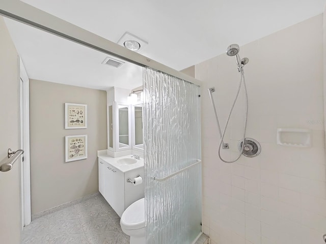 bathroom with a tile shower, vanity, and toilet