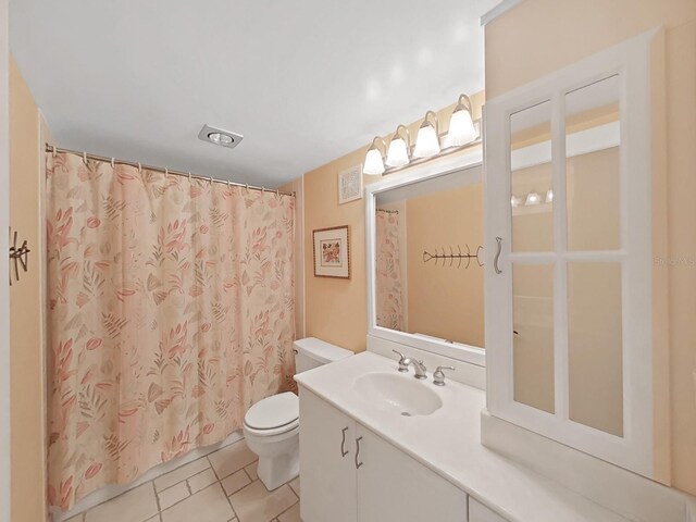 bathroom with tile patterned flooring, vanity, toilet, and walk in shower