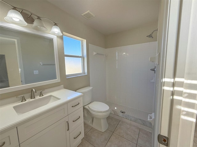 bathroom featuring tile patterned flooring, vanity, tiled shower, and toilet