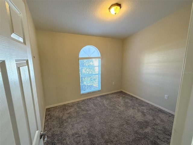 spare room with dark carpet and a textured ceiling