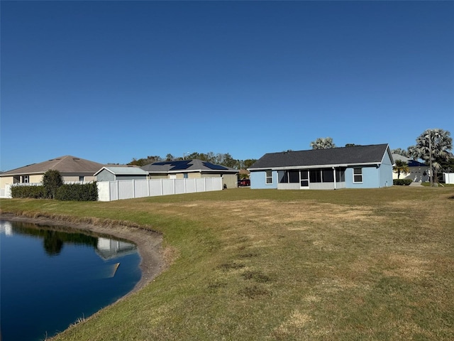 rear view of house featuring a water view and a lawn