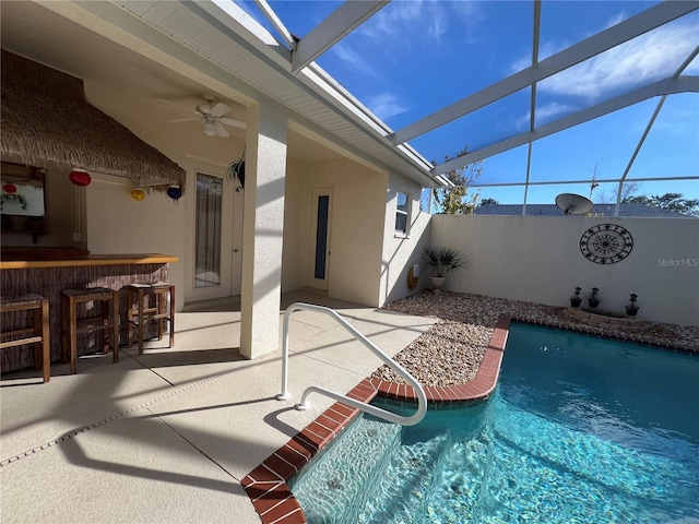 view of pool with a bar, glass enclosure, ceiling fan, and a patio area