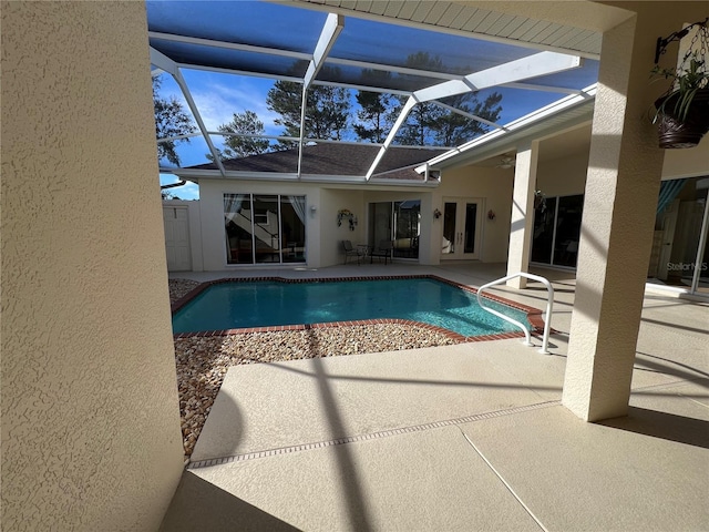 view of swimming pool with glass enclosure, ceiling fan, french doors, and a patio