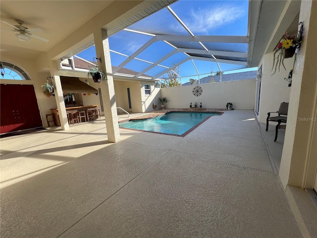 view of swimming pool with ceiling fan, a lanai, an outdoor bar, and a patio