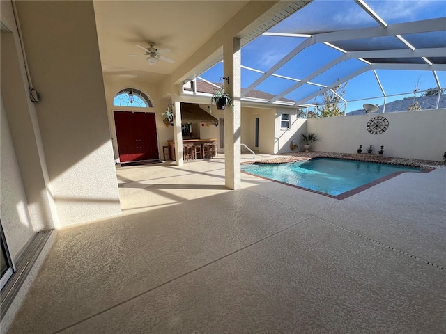 view of pool with exterior bar, a lanai, ceiling fan, and a patio area