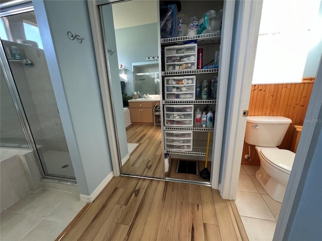 full bathroom with vanity, separate shower and tub, wooden walls, wood-type flooring, and toilet