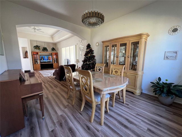 dining room featuring a tray ceiling, ceiling fan with notable chandelier, and dark hardwood / wood-style floors