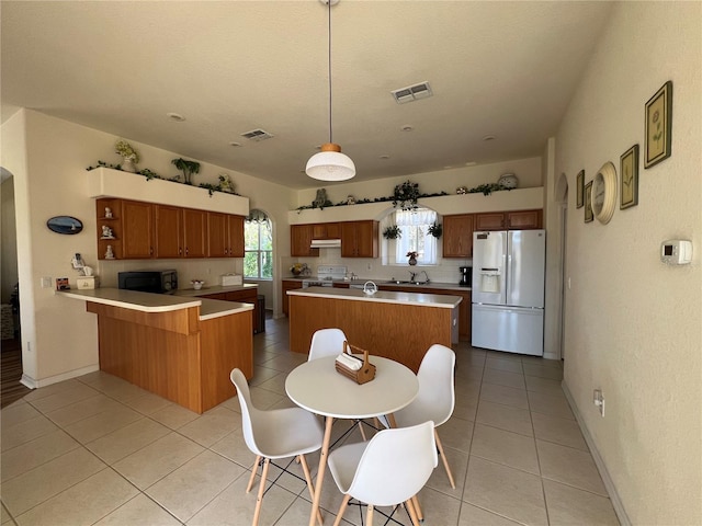 kitchen with kitchen peninsula, decorative light fixtures, white appliances, decorative backsplash, and light tile patterned floors