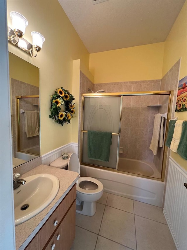 full bathroom with tile patterned flooring, vanity, toilet, and bath / shower combo with glass door