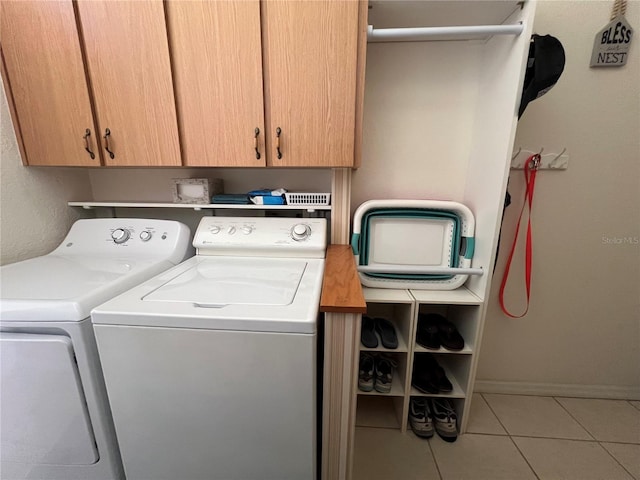 laundry area featuring cabinets, light tile patterned floors, and washer and clothes dryer