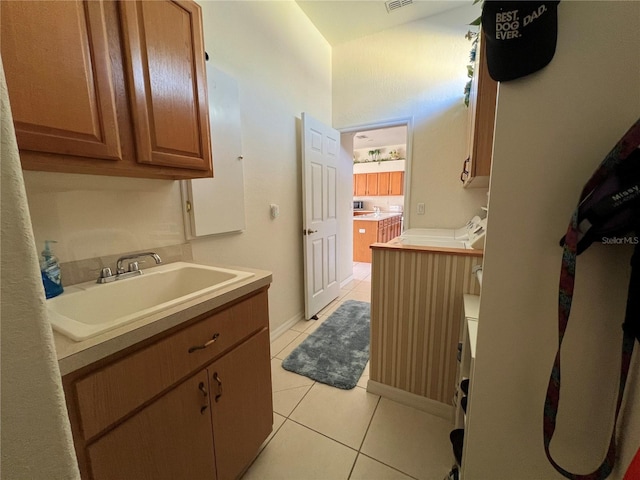 clothes washing area with light tile patterned flooring, cabinets, and sink